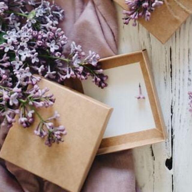 Lila Blumen und offene Geschenkboxen auf lila Tuch
