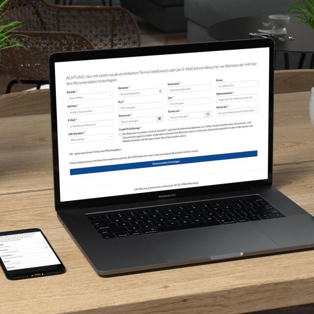 Lap Top steht auf einem Tisch zwischen einem Smartphone und Kopfhörern