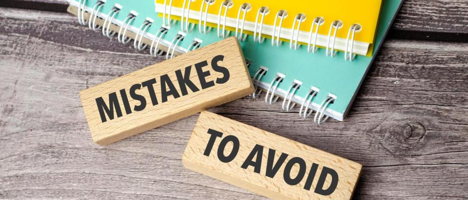 Holzklötze “Fehler, die man vermeiden sollte” liegen auf dem Schreibtisch, zusammen mit Notizbüchern